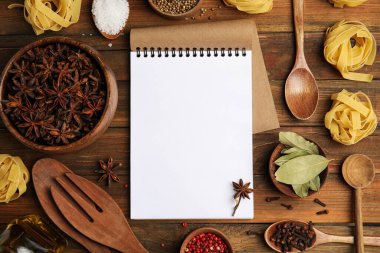 Boş yemek tarifi kitabı, baharatlar, çiğ makarna ve mutfak gereçleri ahşap masa, düz yatak. Metin için boşluk
