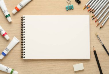 Düz kompozisyon ve ahşap masa üzerinde boş çizim defteri. Metin için boşluk