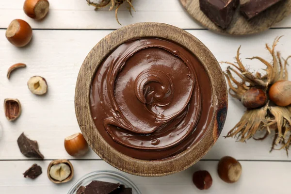 Beyaz ahşap masada fındıklı bir kase lezzetli çikolata ezmesi.