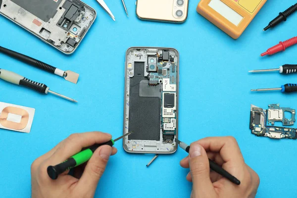 Mann Repariert Kaputtes Smartphone Auf Hellblauem Hintergrund Draufsicht — Stockfoto