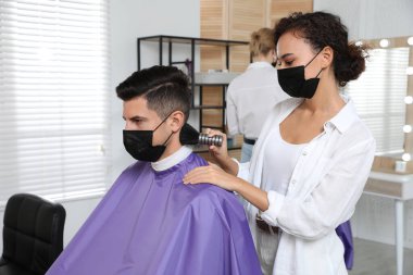 Müşteriyle kuaförde çalışan profesyonel stilist. Coronavirus karantinası sırasında kuaför servisi