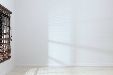 Beyaz duvarları, geniş penceresi ve tahta zemini olan boş bir oda.