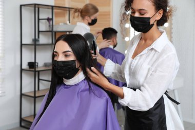 Müşteriyle kuaförde çalışan profesyonel stilist. Coronavirus karantinası sırasında kuaför servisi