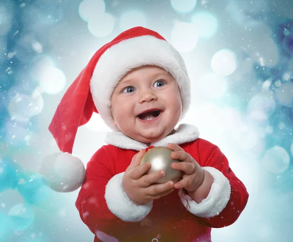 Schattige Baby Kostuum Met Kerstbal Tegen Wazig Feestelijk Licht — Stockfoto