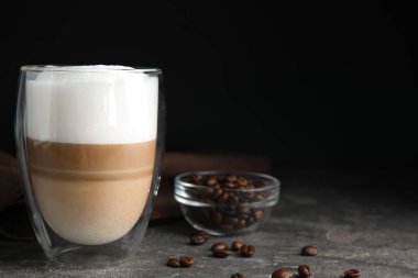 Lezzetli latte macchiato ve kahve çekirdekleri gri masada, mesaj için yer var.