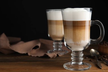 Lezzetli latte macchiato ve kahve çekirdekleri ahşap masada, mesaj için yer var.