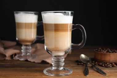 Lezzetli latte macchiato ve kahve çekirdekleri ahşap masada.