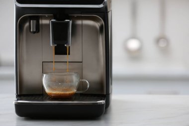 Modern elektrikli espresso makinesi mutfakta beyaz mermer tezgahta kahve yapıyor.