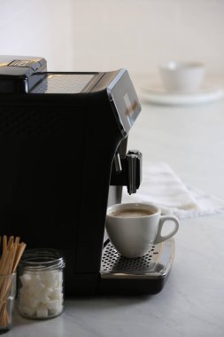 Modern elektrikli espresso makinesi. Mutfaktaki beyaz mermer tezgahta bir fincan kahve.