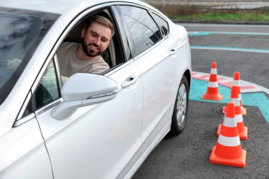 Trafik konisiyle test pistindeki genç adam. Sürücü kursu