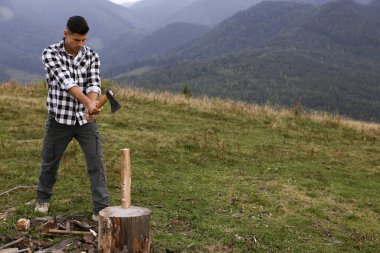 Dağlarda odun kesen baltalı yakışıklı bir adam.