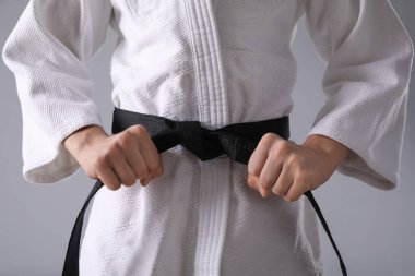 Gri arka planda siyah kuşakla Keikogi 'de dövüş sanatları ustası, yakın plan.