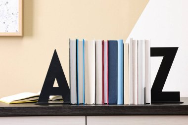 Minimalist letter bookends with books on table indoors clipart