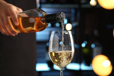 Barmen bardaklara beyaz şarap dolduruyor, yakın plan.