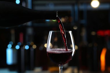 Kırmızı şarabı bulanık arka planda bardaklara dök. Yakın plan.