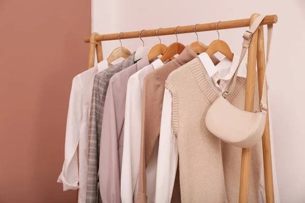 Bastidor Con Diferentes Ropa Elegante Bolsa Cerca Pared Blanca Interior —  Fotos de Stock