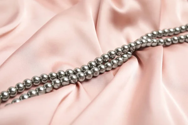 精致的粉红丝绸上美丽的银珠 — 图库照片