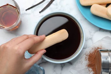 Kadın beyaz mermer masada tiramisu keki yapıyor.