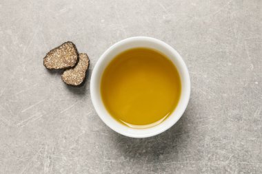 Taze trüf mantarı ve yağlı kase açık gri masada, düz yatıyordu.