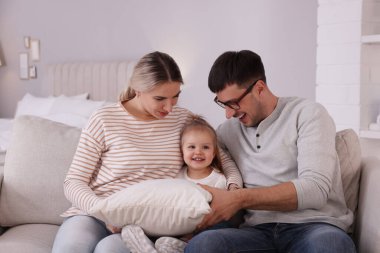 Küçük kızı olan bir aile evdeki kanepede birlikte vakit geçiriyor.