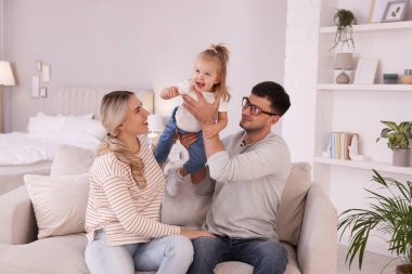 Küçük kızı olan bir aile evdeki kanepede birlikte vakit geçiriyor.