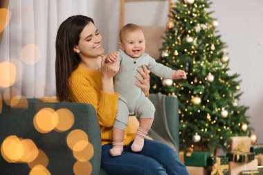 Mutlu, genç bir anne ve tatlı bebeği Noel için dekore edilmiş bir odada. Kış tatili