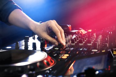 DJ, gece kulübünde modern konsol karıştırıcısında müzik yaratıyor.