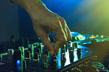 DJ, gece kulübünde modern konsol karıştırıcısında müzik yaratıyor.