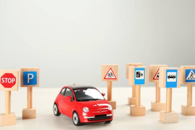 Birçok farklı minyatür yol işaretleri ve beyaz ahşap masa üzerinde araba, yazı için yer. Sürücü kursu
