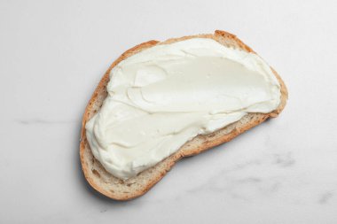 Beyaz mermer masada lezzetli krem peynirli bir dilim ekmek, üst manzara.