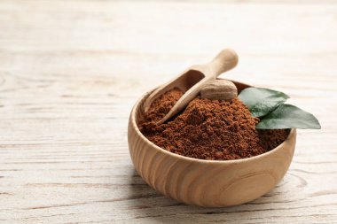 Nutmeg tozu ve yeşil yapraklı tohum beyaz ahşap masada, metin için yer var.