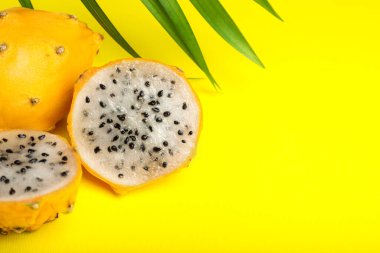 Lezzetli kesim ve tüm ejderha meyveleri (pitahaya) sarı arka planda, yakın plan. Metin için boşluk
