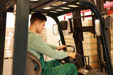 Depoda forklift kamyonuyla karton kutular düzenleyen bir işçi. Lojistik kavramı