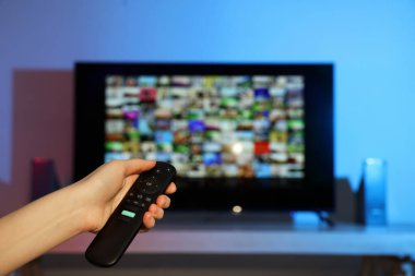 Televizyonda uzaktan kumandayla kanal değiştiren bir kadın. Metin için boşluk