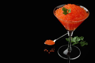 Siyah arka planda lezzetli kırmızı havyar ve maydanoz. Metin için boşluk