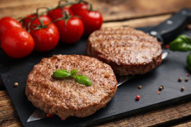 Ahşap masada servis edilen leziz ızgara hamburger köfteleri, yakın plan.