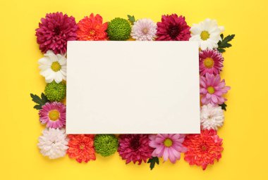Güzel kasımpatı çiçeklerinden yapılmış bir çerçeve ve sarı arka planda boş bir kart. Metin için boşluk