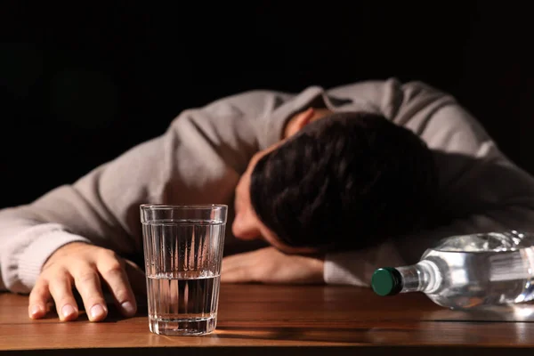 Verslaafde Man Met Alcoholische Drank Aan Houten Tafel Tegen Zwarte — Stockfoto