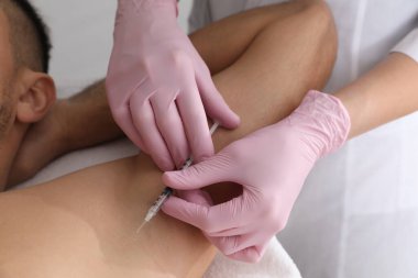Kozmetik uzmanı, insanın koltuk altına iğne yapıyor, yakın plan. Hiperhidroz tedavisi