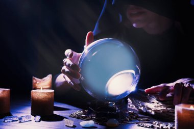 Kahin, kristal küreyi kullanarak karanlıkta geleceği tahmin ediyor. Yakın plan. Falcı.