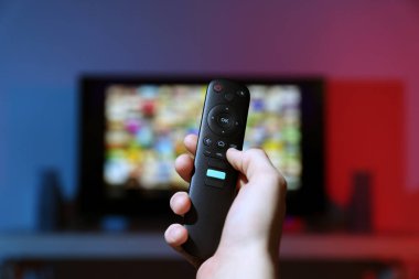 Televizyonda uzaktan kumandayla kanal değiştiren kadın, yakın çekim.