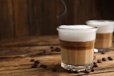 Lezzetli latte macchiato ve kahve çekirdekleri ahşap masada, mesaj için yer var.