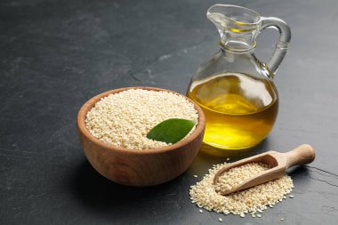 Siyah masaya bir sürahi susam yağı ve tohumlar.