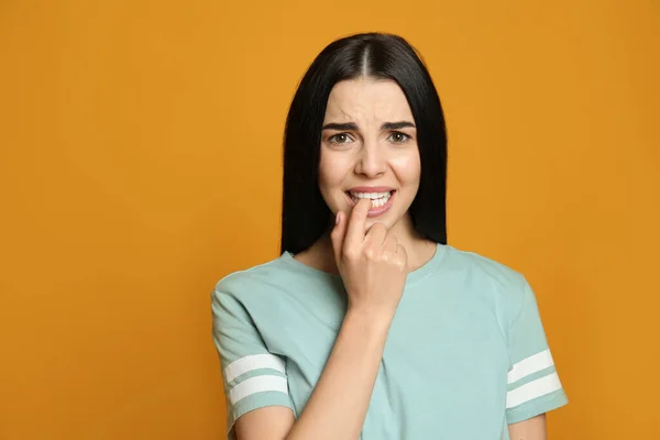 Junge Frau Beißt Ihre Nägel Auf Gelbem Hintergrund — Stockfoto