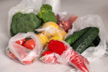 Plastik torbalar ve taze ürünler beyaz masada, yakın plan.