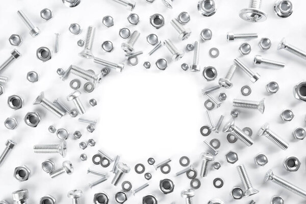 Frame of different metal bolts and nuts on white background, top view. Space for text