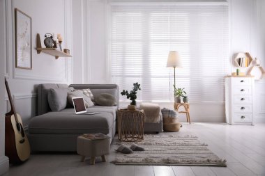 Rahat gri kanepeli oturma odası ve pencerenin yanındaki iç dekorasyonlar.