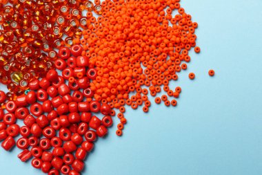 Açık mavi zemin üzerinde farklı boncuklar yığını, düz yatıyordu