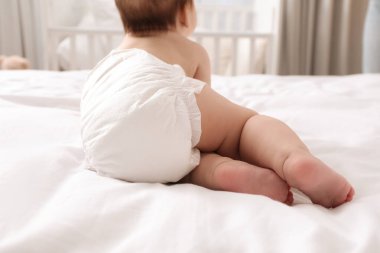 Bezli küçük bir bebek. Yatakta, arka planda.