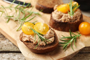 Lezzetli etli etli ekmek dilimleri, domates ve biberiye ahşap masada, yakın plan.